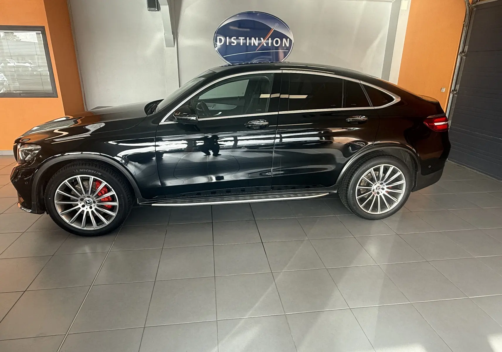 Vue de profil côté gauche d’un Mercedes GLC Coupé noir 2018 avec jantes AMG et étriers de frein rouges.