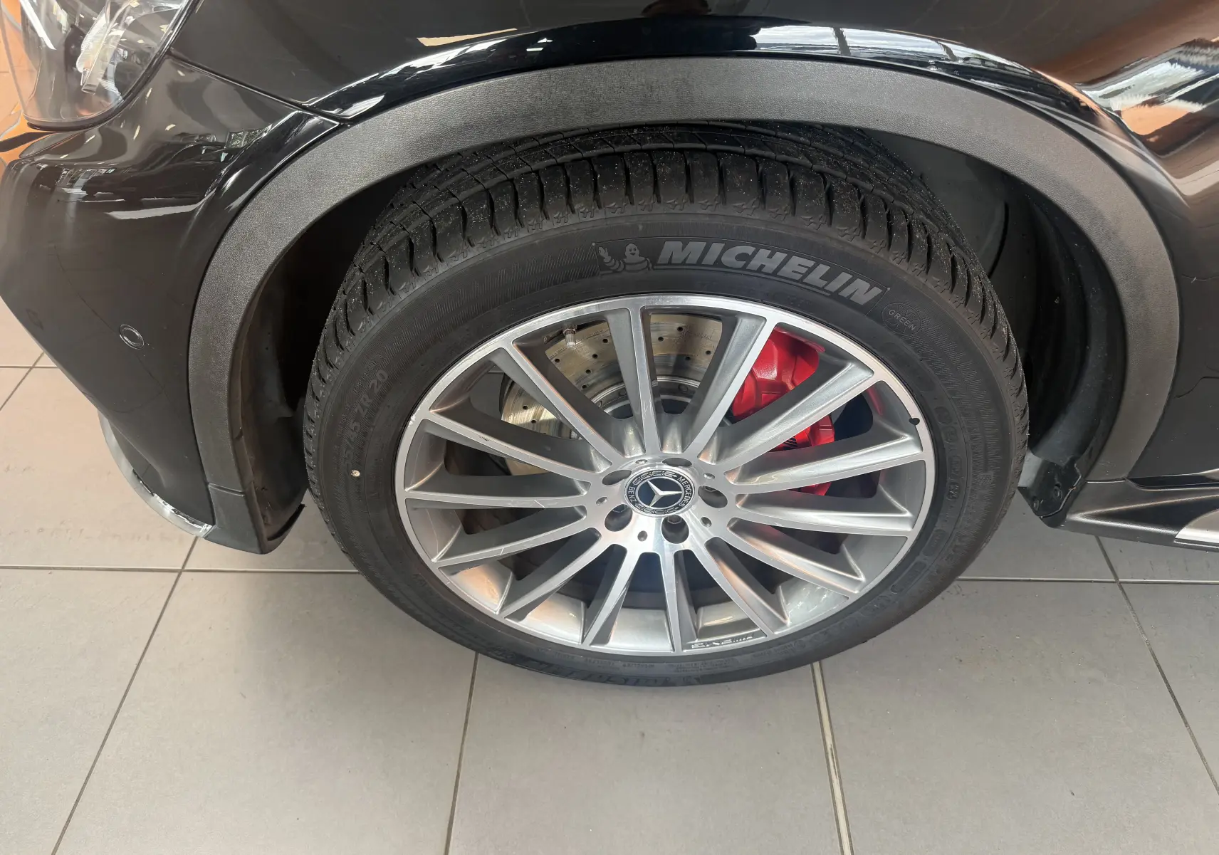 Gros plan sur la roue avant gauche d’un Mercedes GLC Coupé noir, avec jante AMG argent et étrier de frein rouge.