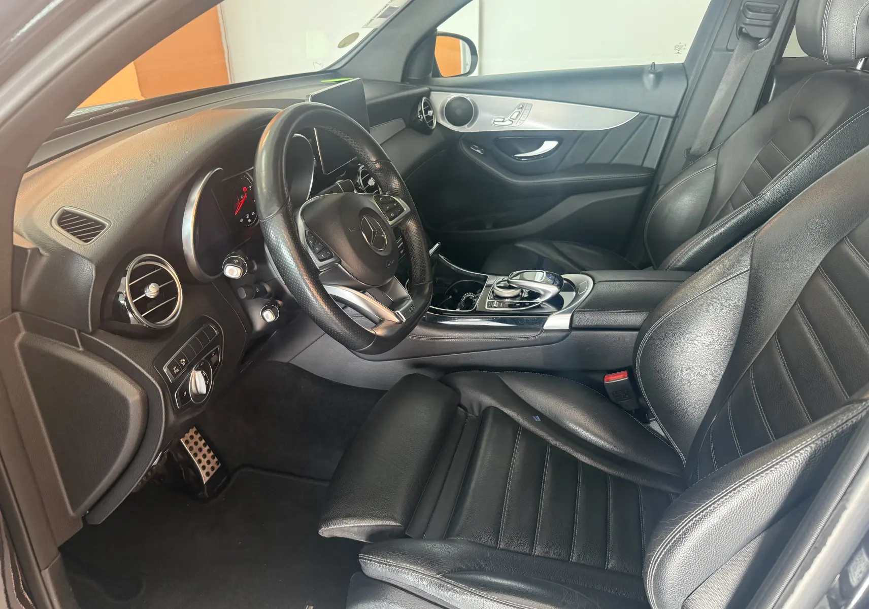 Vue intérieure côté conducteur du Mercedes GLC Coupé 2.2 170d Sportline AMG 2018 avec sièges cuir noirs et console centrale brillante.
