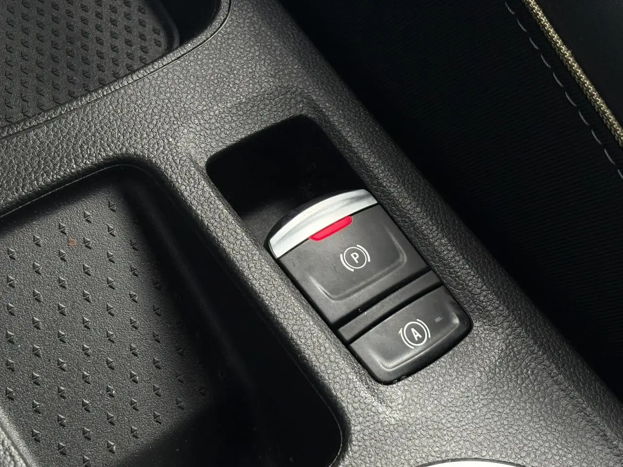 Gros plan sur la console centrale noire de la Renault SYMBIOZ E-Tech avec boutons frein de parking et auto-hold.