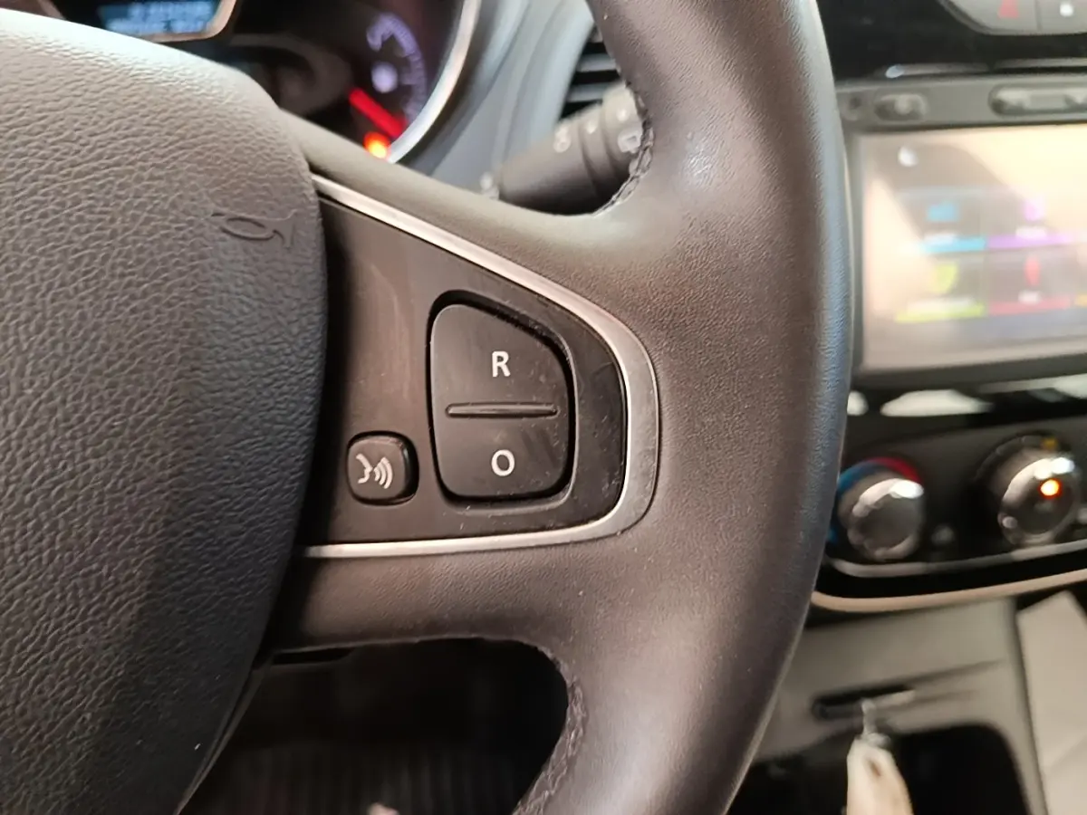Gros plan sur le volant noir multifonctions du Renault Captur 2018 avec tableau de bord et écran tactile flous en arrière-plan.