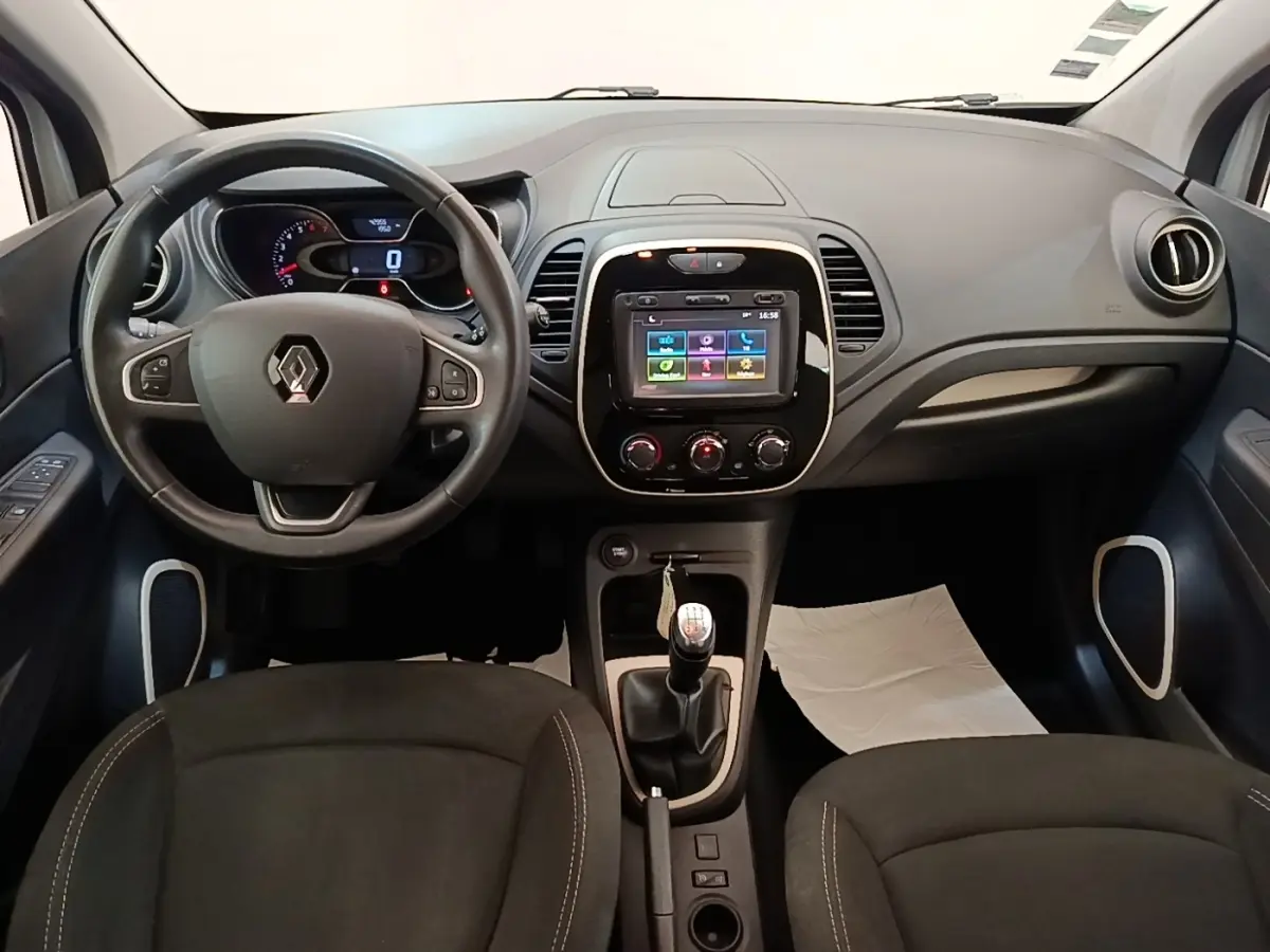 Vue intérieure frontale du tableau de bord du Renault Captur gris clair avec volant multifonctions et écran tactile central.