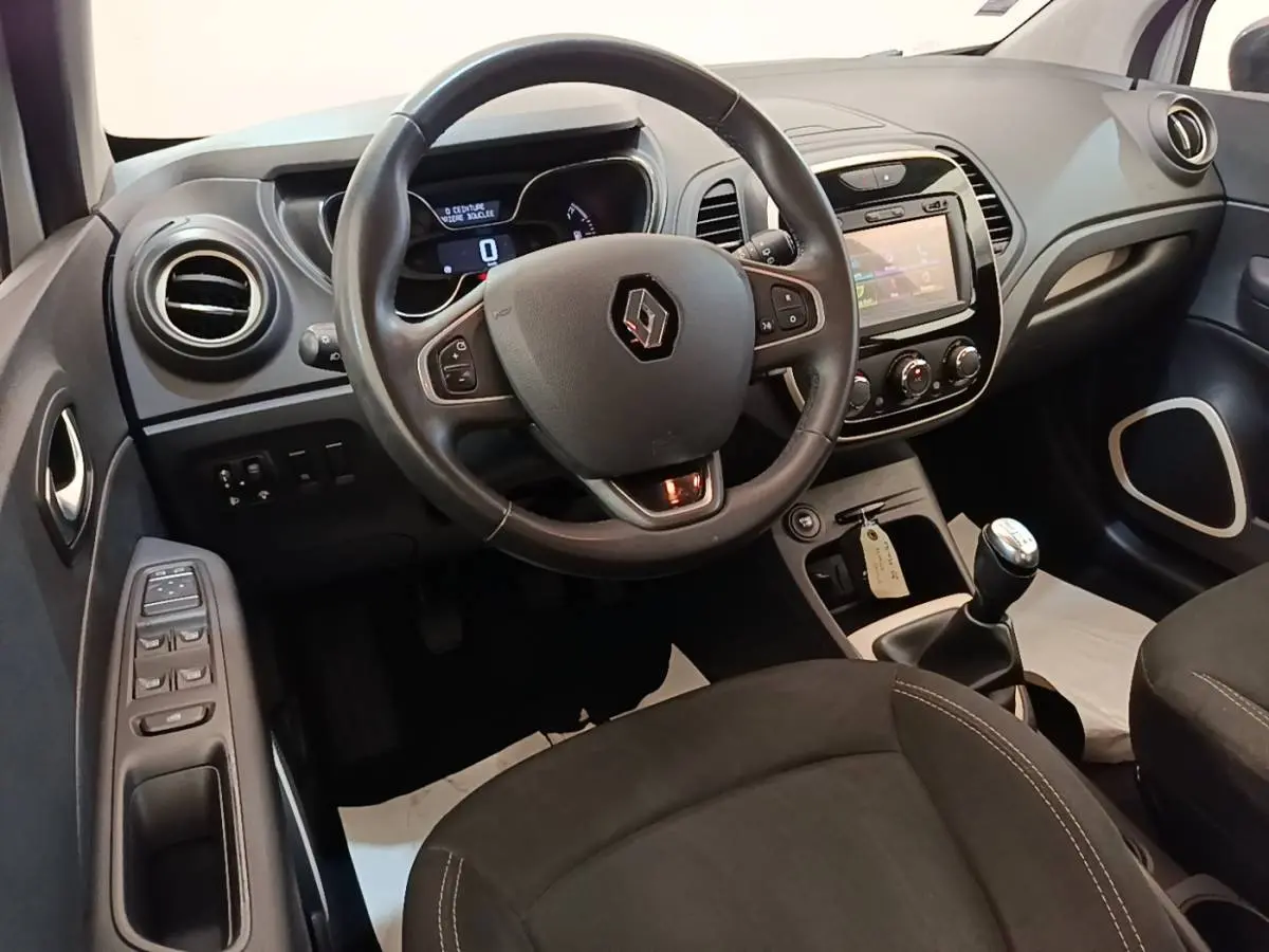 Vue intérieure du poste de conduite Renault Captur gris clair 2018, volant multifonction et tableau de bord avec écran tactile.