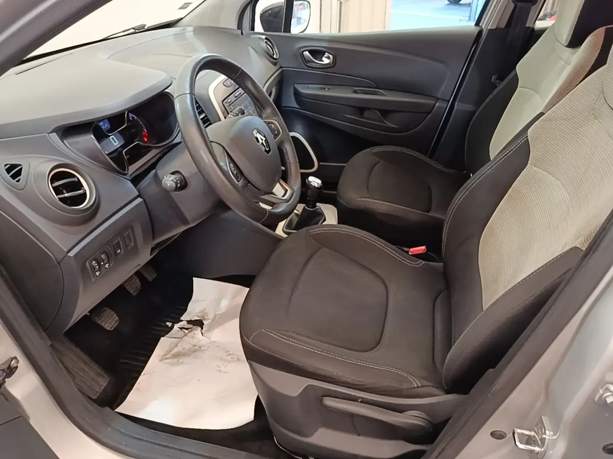 Vue intérieure côté conducteur du Renault Captur gris clair 2018, montrant sièges noirs et tableau de bord avec volant multifonctions.