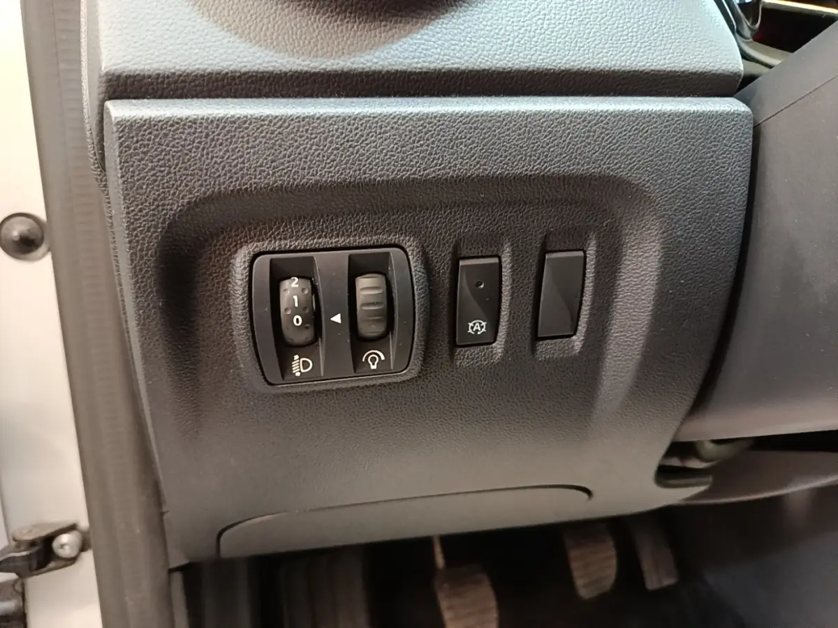 Gros plan sur les commandes de réglage des phares et autres boutons côté gauche du tableau de bord d’un Renault Captur gris clair 2018.