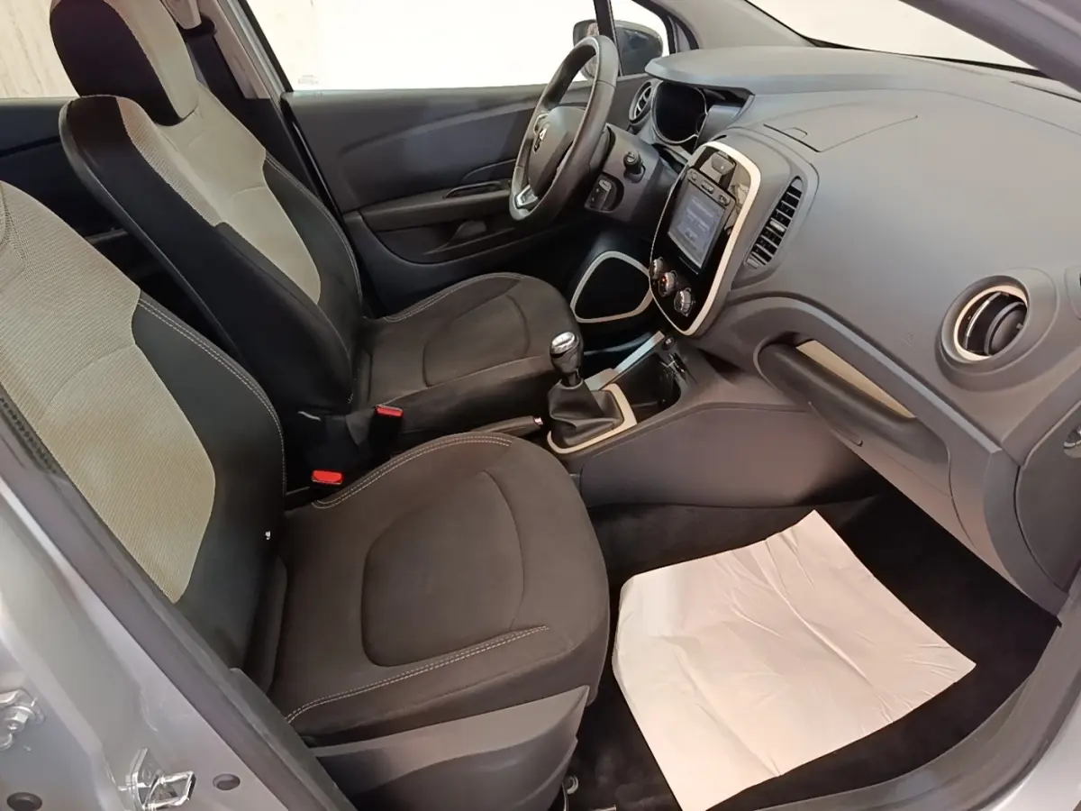 Vue intérieure côté conducteur de la Renault Captur gris clair 2018, montrant les sièges et le tableau de bord avec écran tactile.