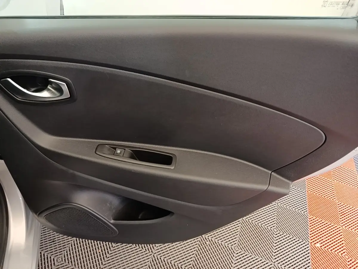 Gros plan sur la porte intérieure côté droit du Renault Captur gris clair, avec poignée et commande de vitre électrique.