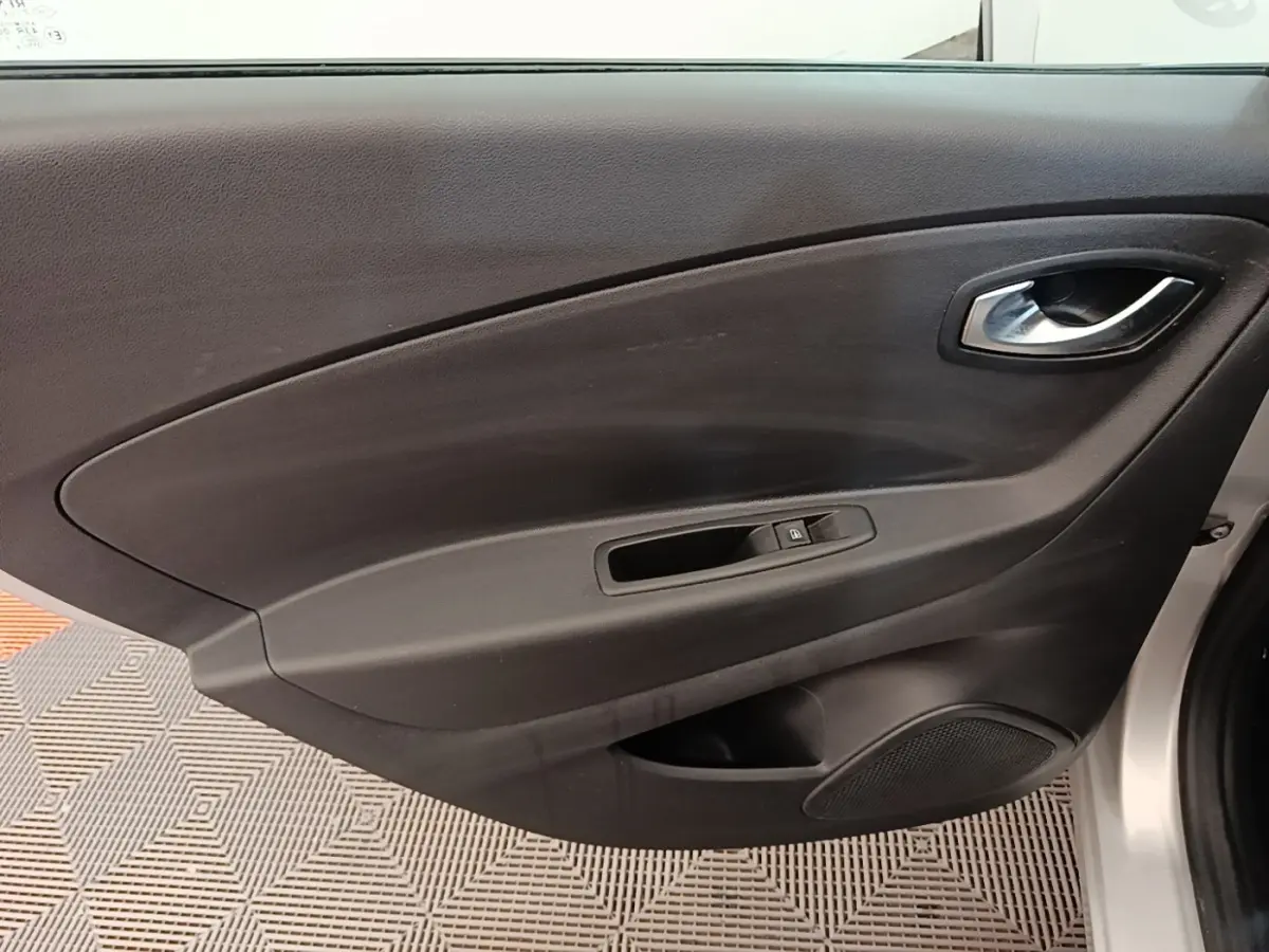 Vue intérieure côté gauche de la porte avant d’un Renault Captur gris clair avec commande de vitre et poignée intégrée.