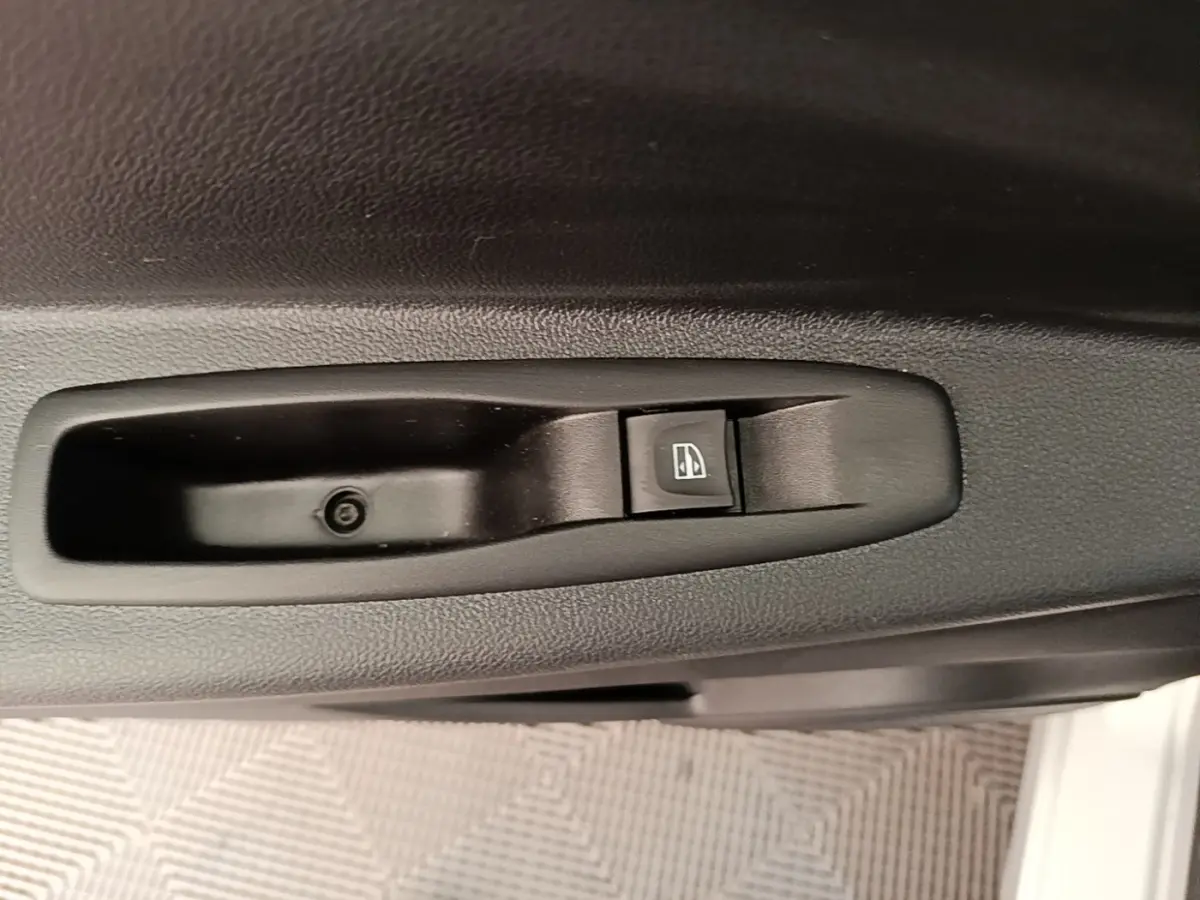Gros plan sur le bouton de commande de la vitre électrique côté conducteur d’un Renault Captur gris clair 2018.