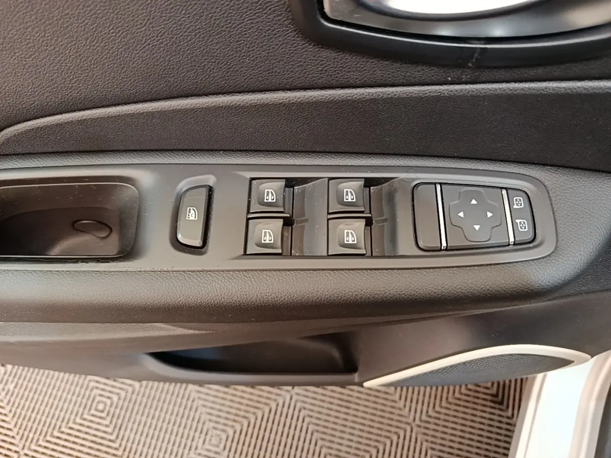 Vue rapprochée des commandes des vitres électriques et réglages des rétroviseurs côté conducteur d'un Renault Captur gris clair.
