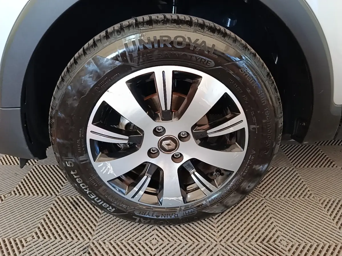 Gros plan sur la roue avant droite d’un Renault Captur gris clair, mettant en valeur la jante alliage et le pneu Uniroyal.
