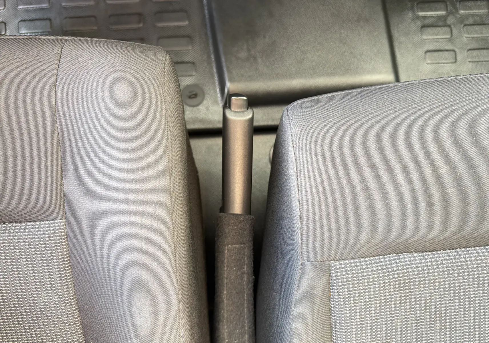 Vue rapprochée de la poignée de frein à main entre deux sièges gris du Fiat Scudo Fourgon XL 180 2025.