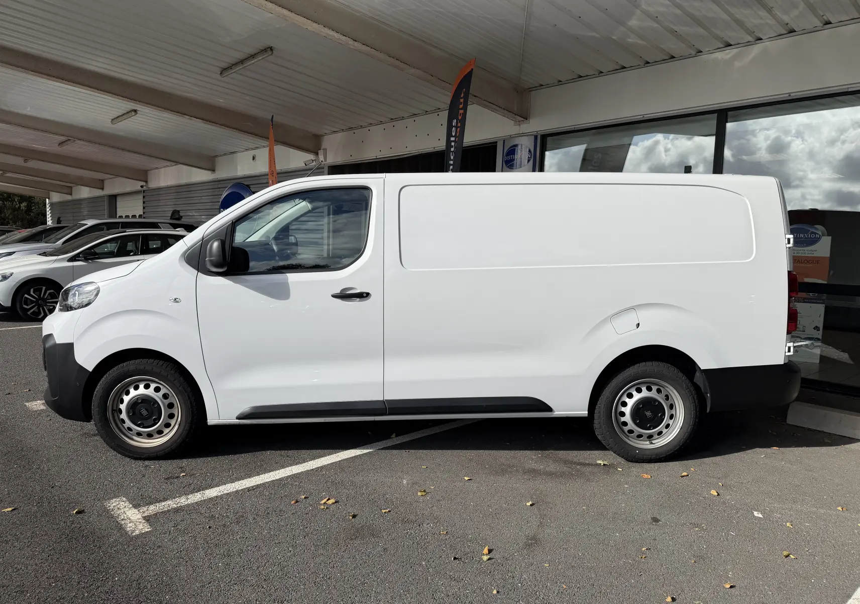 Vue de profil côté gauche d’un FIAT Scudo Fourgon blanc 2025 avec jantes tôles grises et porte coulissante fermée.