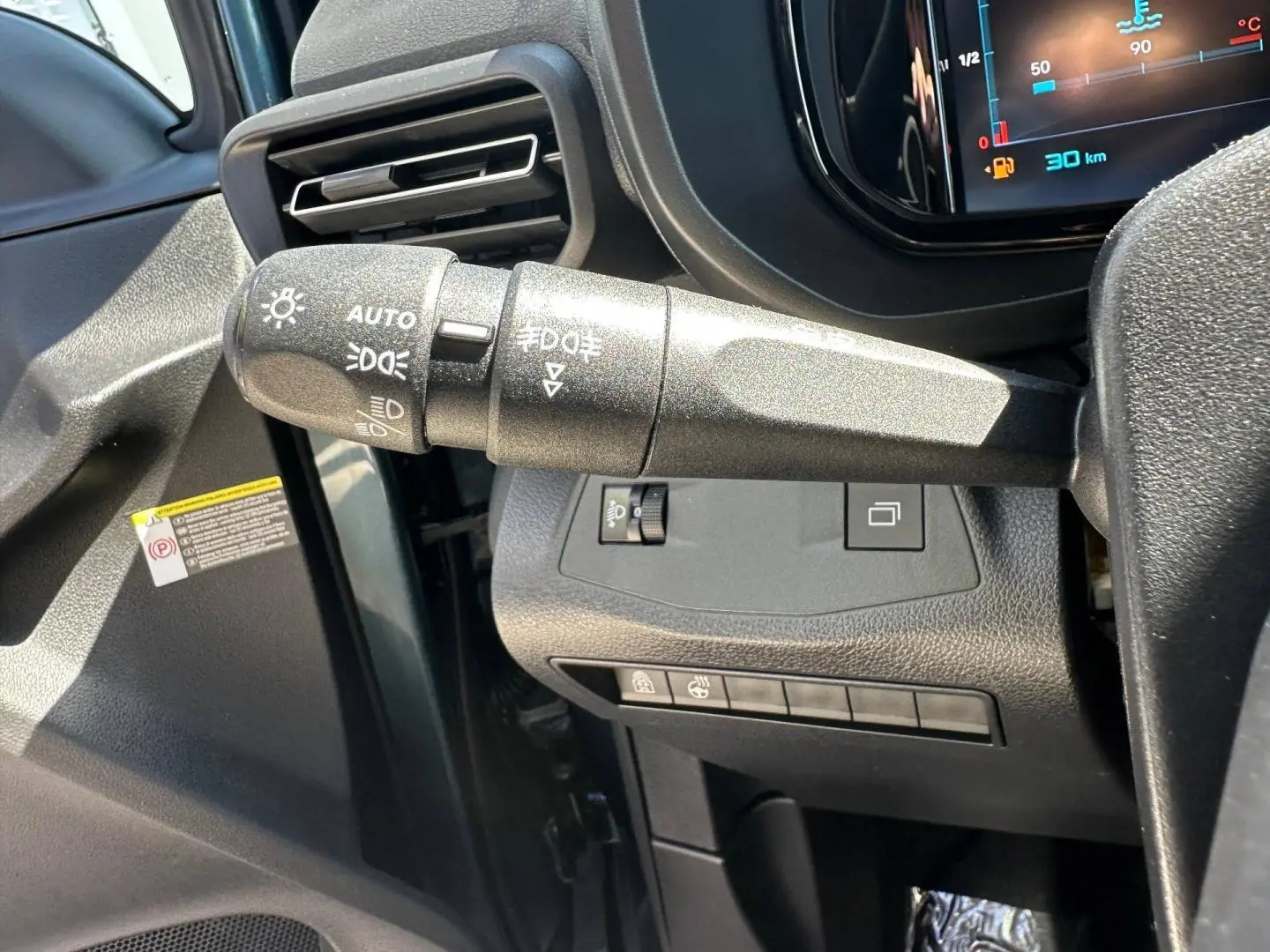 Gros plan sur la commande des phares à gauche du volant dans l’habitacle du Citroën Berlingo Kiama Blue.