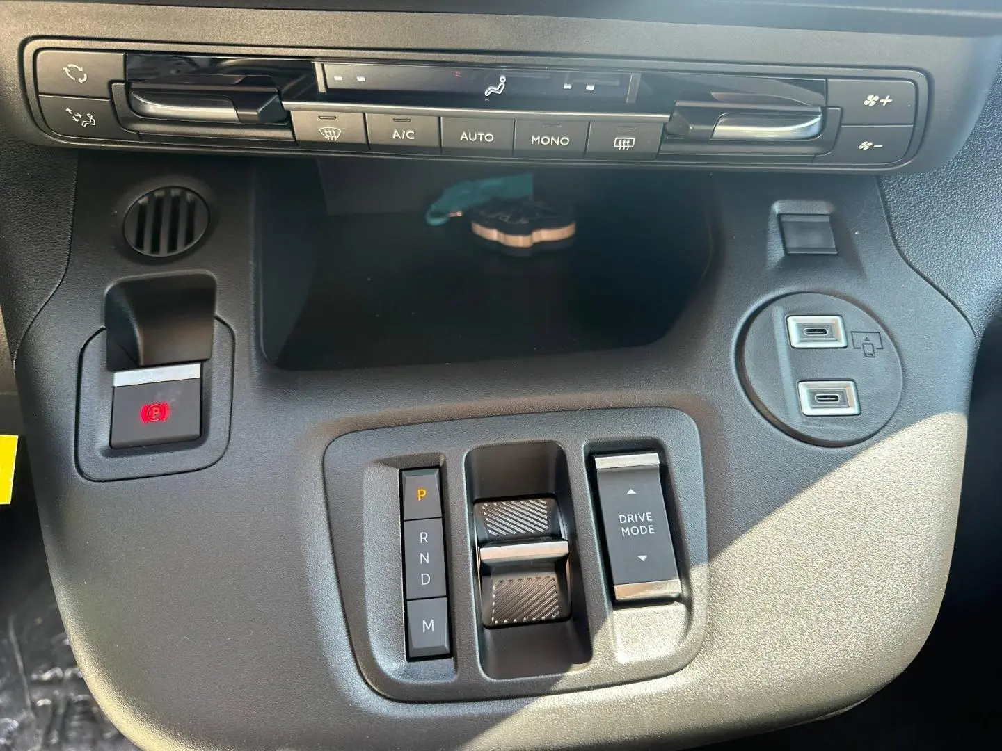 Vue rapprochée de la console centrale noire du Citroën Berlingo 2026 avec commandes de climatisation et boîte auto.
