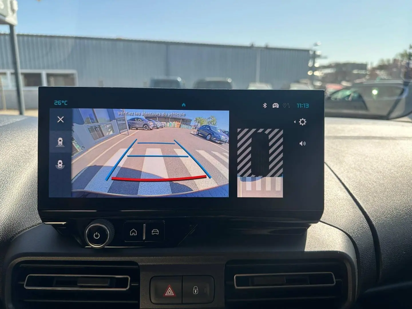 Écran tactile intérieur du Citroën Berlingo montrant la caméra de recul avec vue arrière sur parking et marquage au sol.