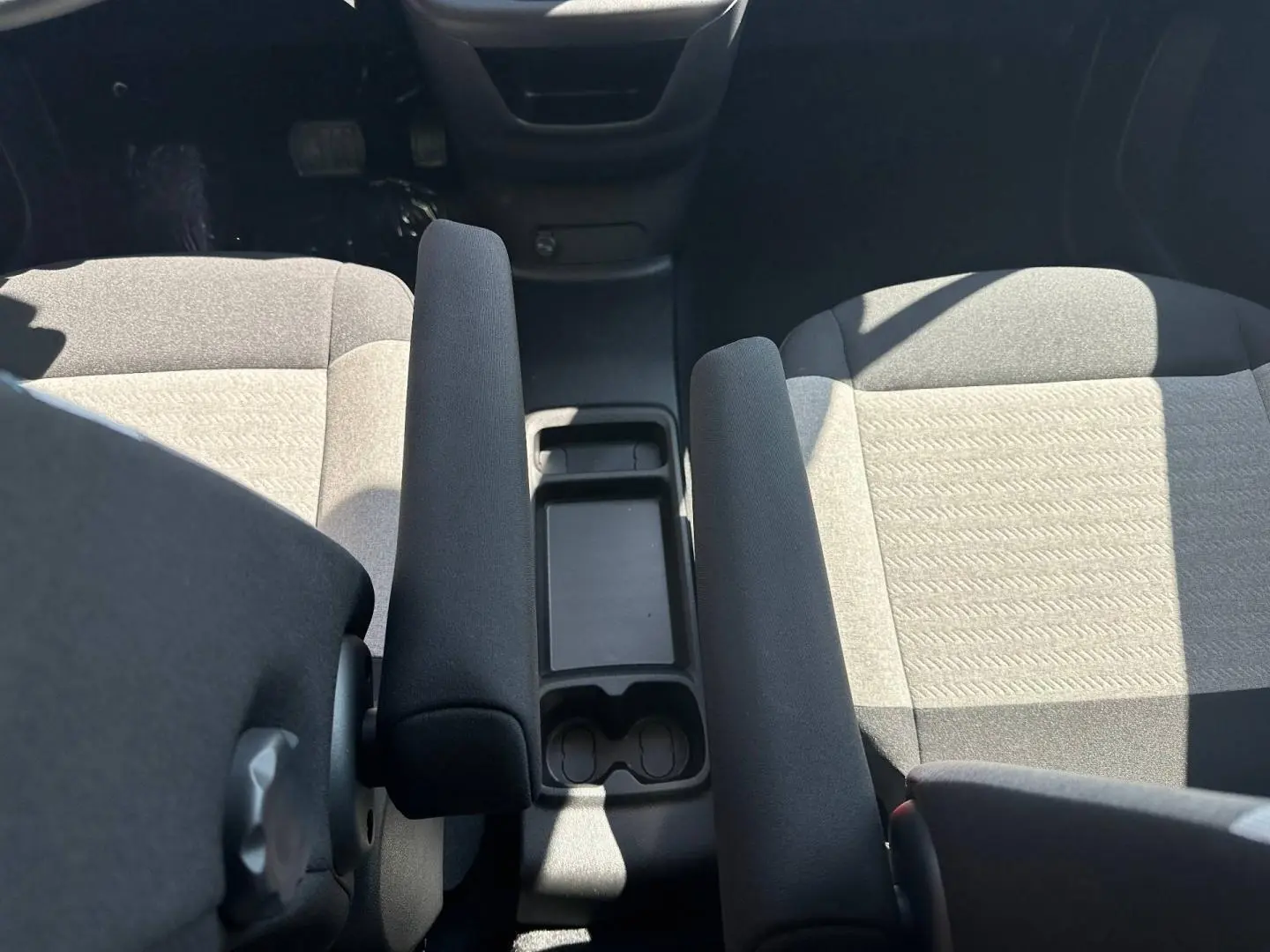 Vue intérieure rapprochée du Citroën Berlingo 2026, montrant les sièges avant gris et l'accoudoir central noir.