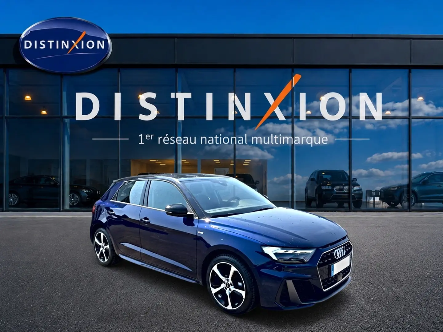 Audi A1 Sportback bleu foncé/noir en 3/4 avant, avec jantes alu et toit noir devant showroom Distinxion.