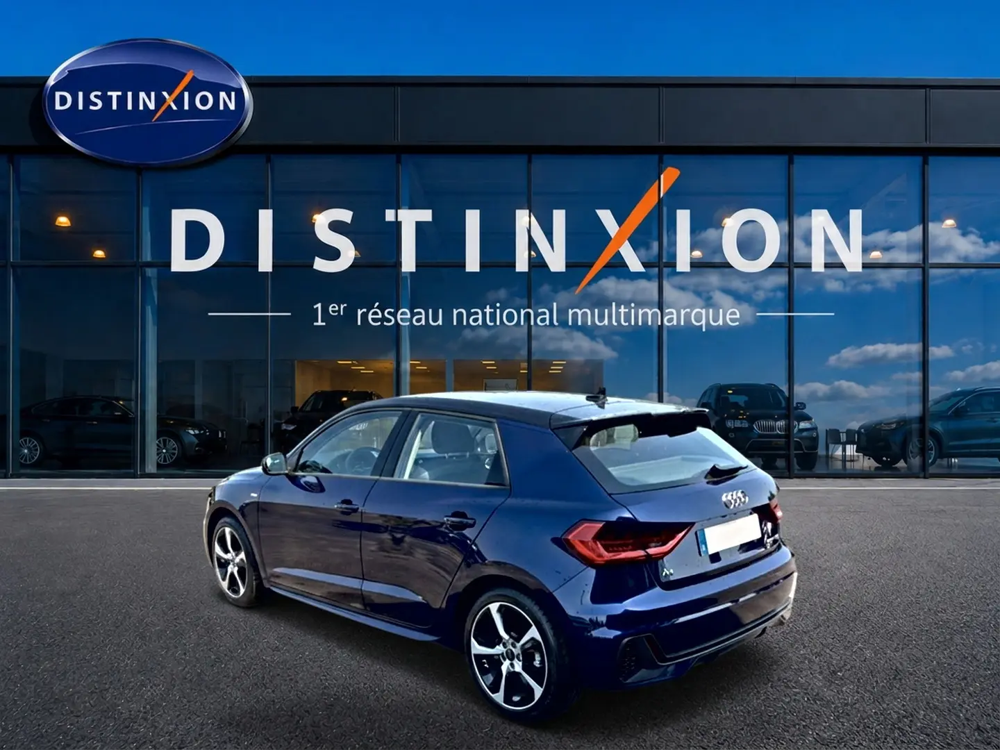 Audi A1 Sportback bleu foncé vue 3/4 arrière droit, avec jantes alu et becquet arrière distinctifs.