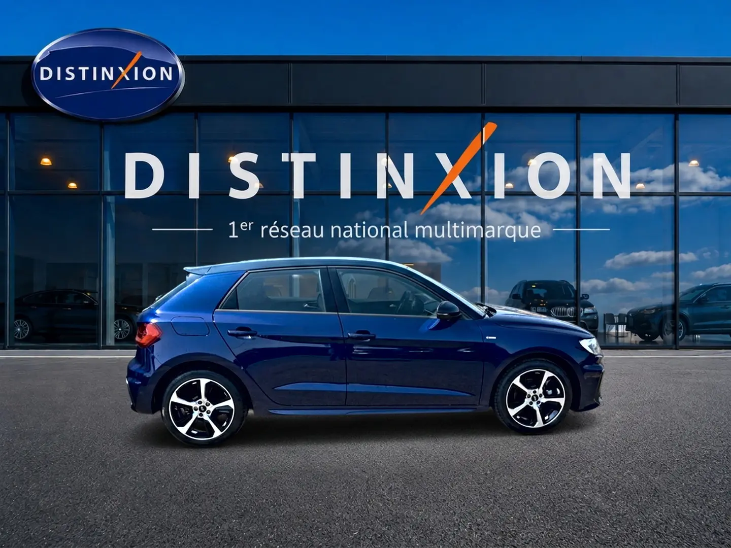Audi A1 Sportback bleu foncé vue de profil côté gauche, avec jantes alliage et toit noir devant vitrine Distinxion.