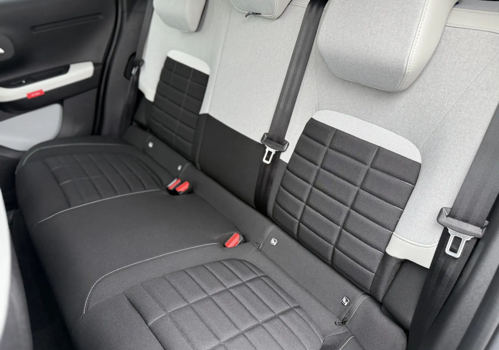 Vue intérieure arrière des sièges arrière gris clair et noir de la Citroën C3 hybride 2026 avec ceintures de sécurité visibles.