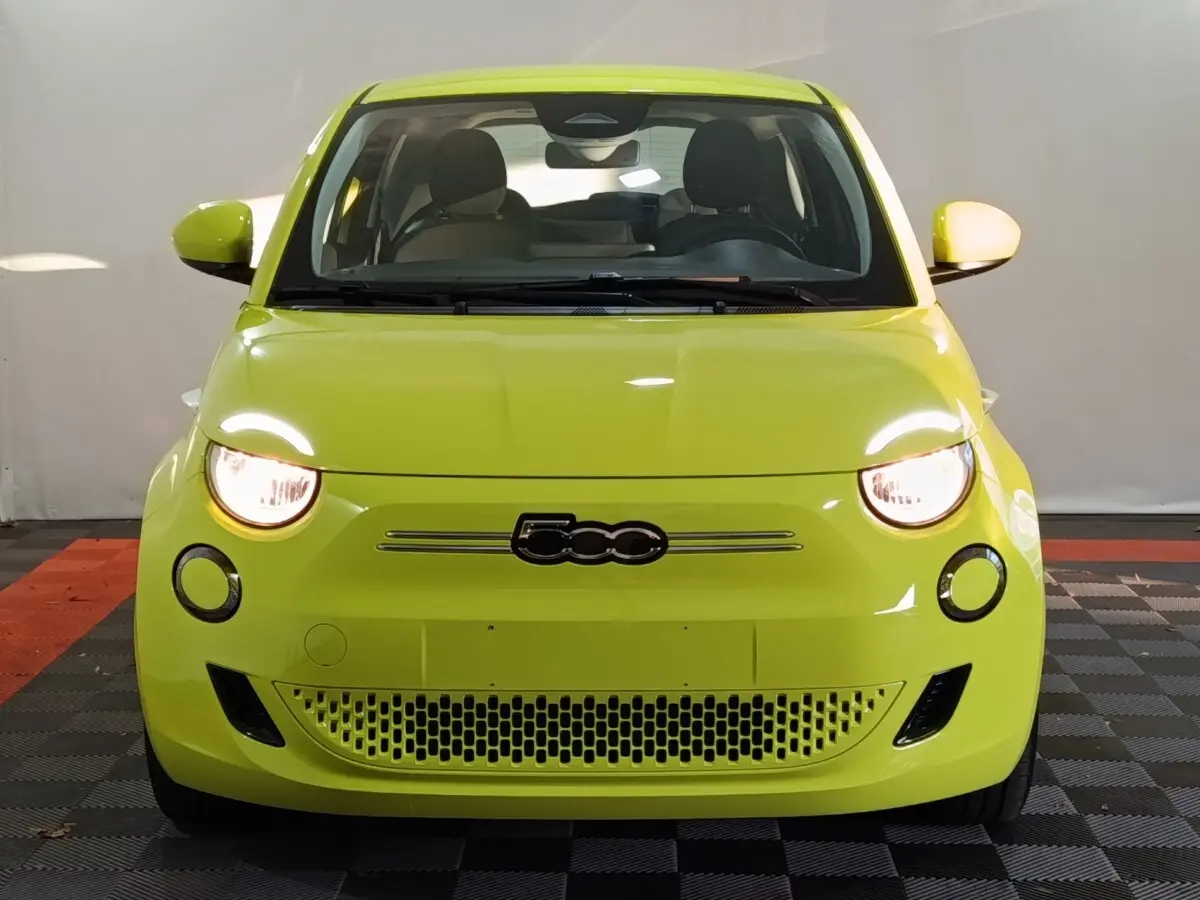 Vue frontale d'une FIAT 500 BEV 24KWH jaune vif avec phares allumés et logo 500 centré sur la calandre.