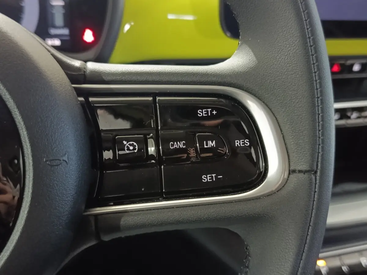 Gros plan sur le volant en cuir synthétique noir du Fiat 500 BEV 24KWH 2024, avec commandes multifonctions visibles.