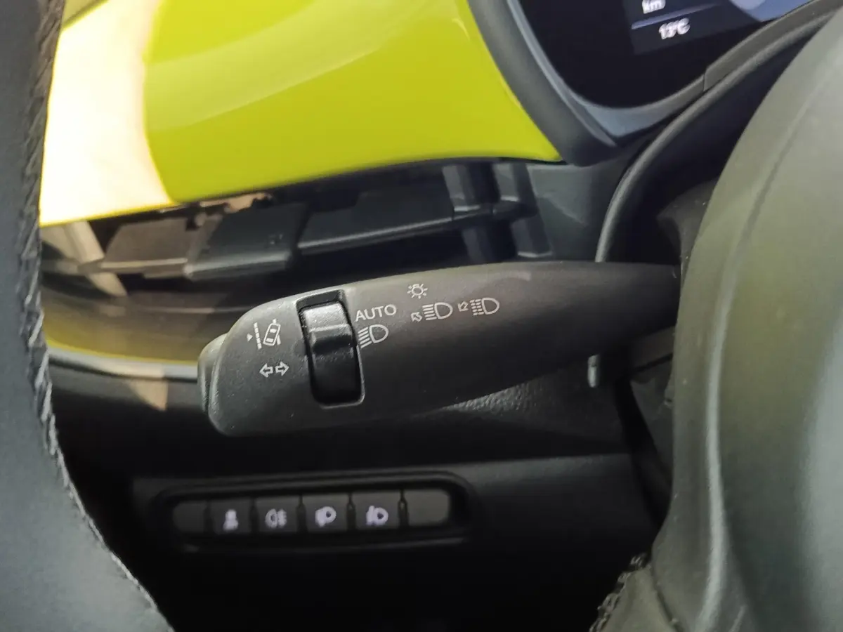 Gros plan sur la manette de commande des feux et clignotants, avec partie intérieure jaune vif visible du Fiat 500 électrique 2024.