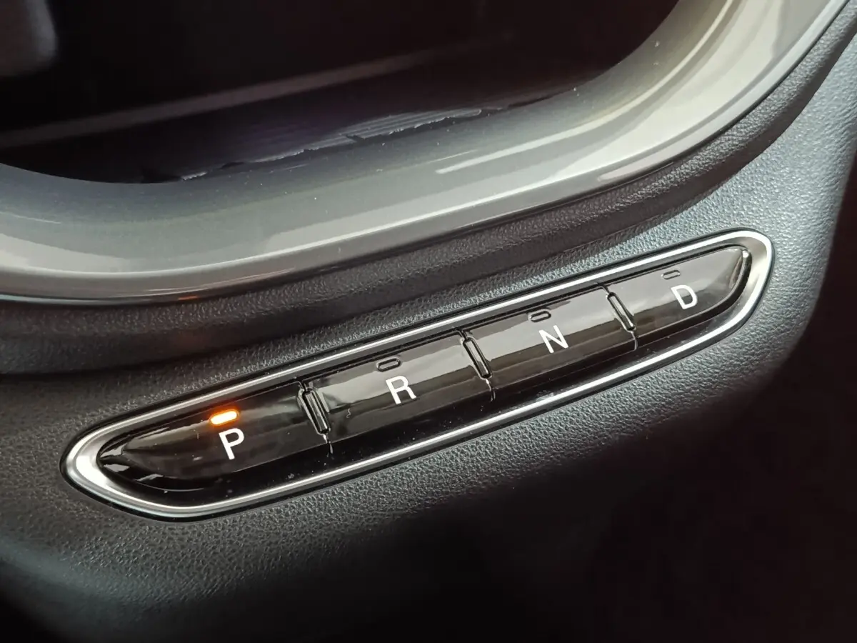 Gros plan sur les boutons de la boîte automatique noire avec indication orange sur la position "P" dans une Fiat 500 BEV jaune.