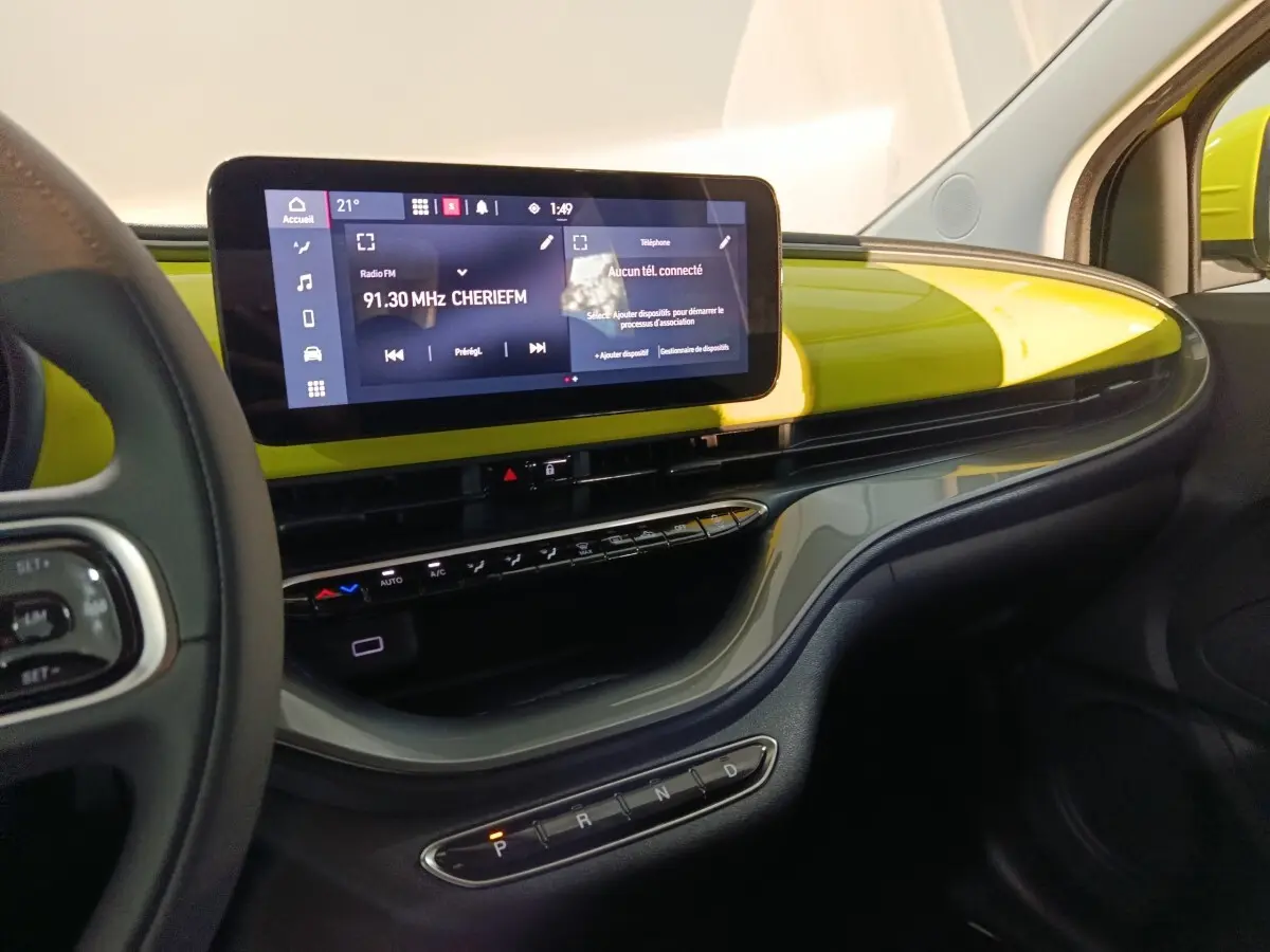 Vue intérieure côté passager du tableau de bord jaune vif du Fiat 500 BEV 2024 avec écran tactile central large.
