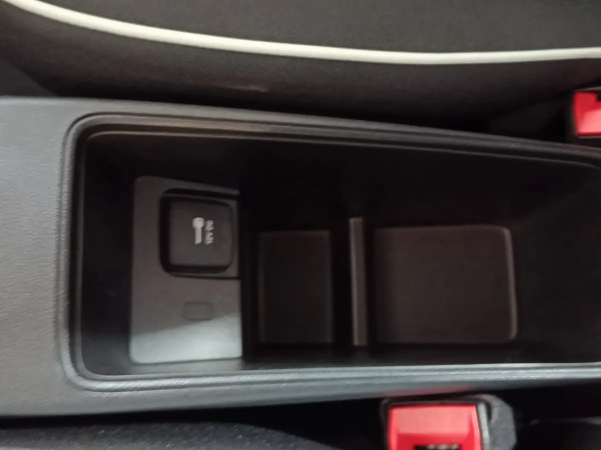 Vue rapprochée de la console centrale noire du Fiat 500 BEV 24KWH avec prise 12V et bouton de verrouillage.
