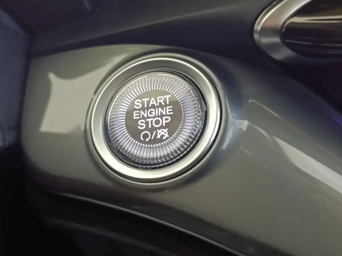 Bouton démarrage Start Engine Stop en gros plan sur tableau de bord gris du Fiat 500 électrique 2024.