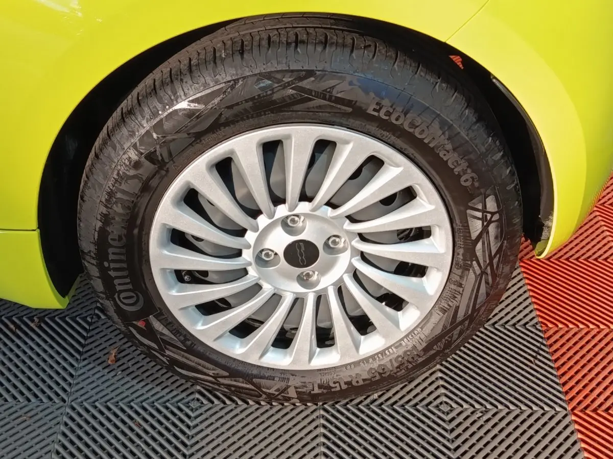 Gros plan sur la roue avant droite d'une FIAT 500 BEV 24KWH jaune avec jante argentée à rayons fins.