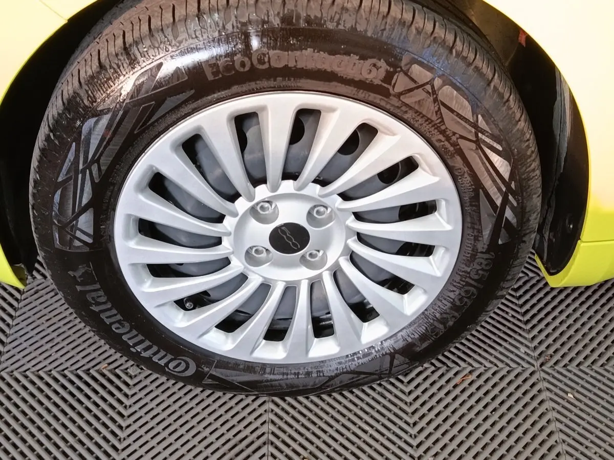 Gros plan sur la roue avant droite d'une FIAT 500 BEV 24KWH jaune avec jante argentée multibranches.