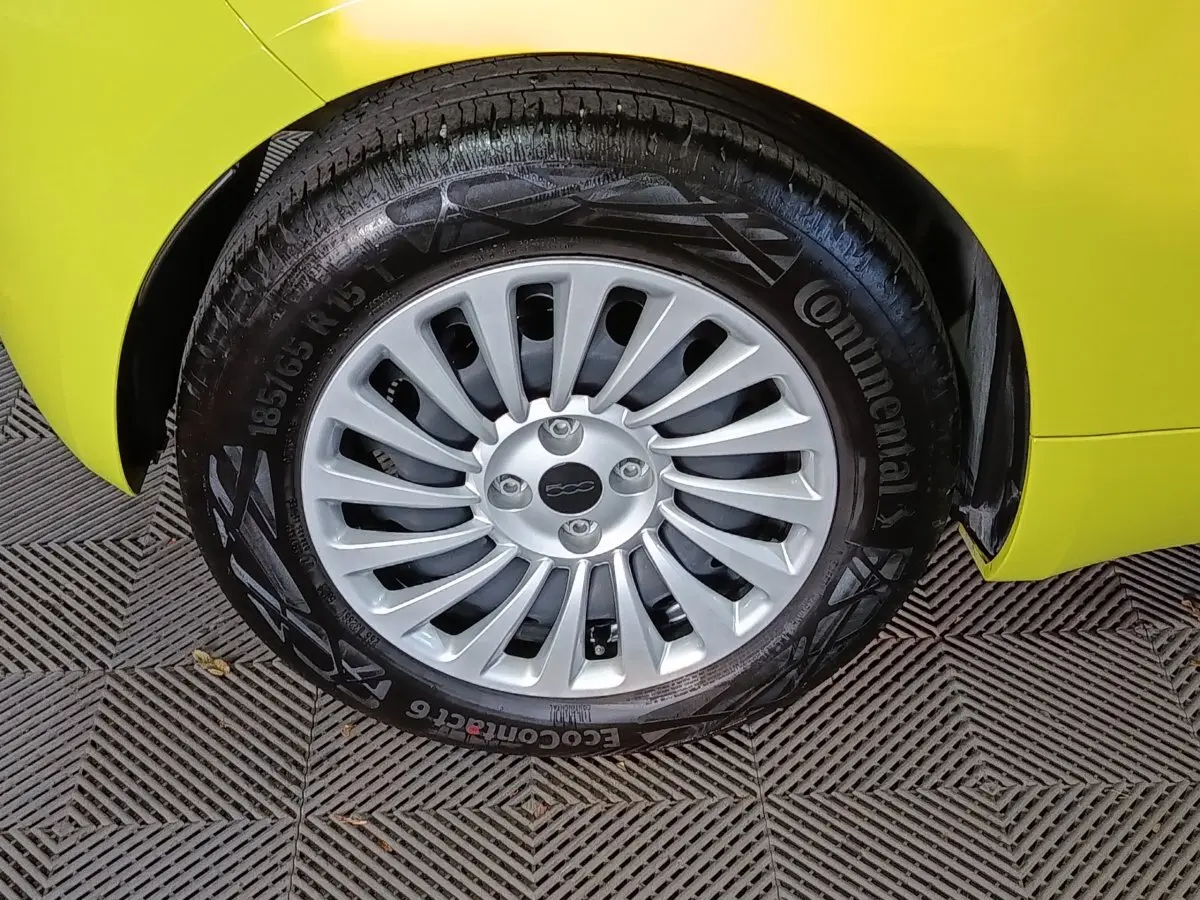 Gros plan sur la roue avant droite d'une FIAT 500 BEV 24KWH jaune, avec jante argentée et pneu Continental.