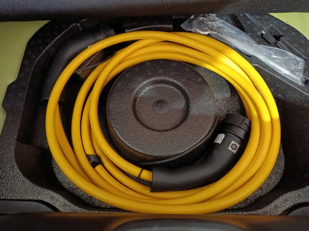 Câble de recharge jaune enroulé dans le coffre d'une Fiat 500 BEV 24kWh électrique, vue de dessus.