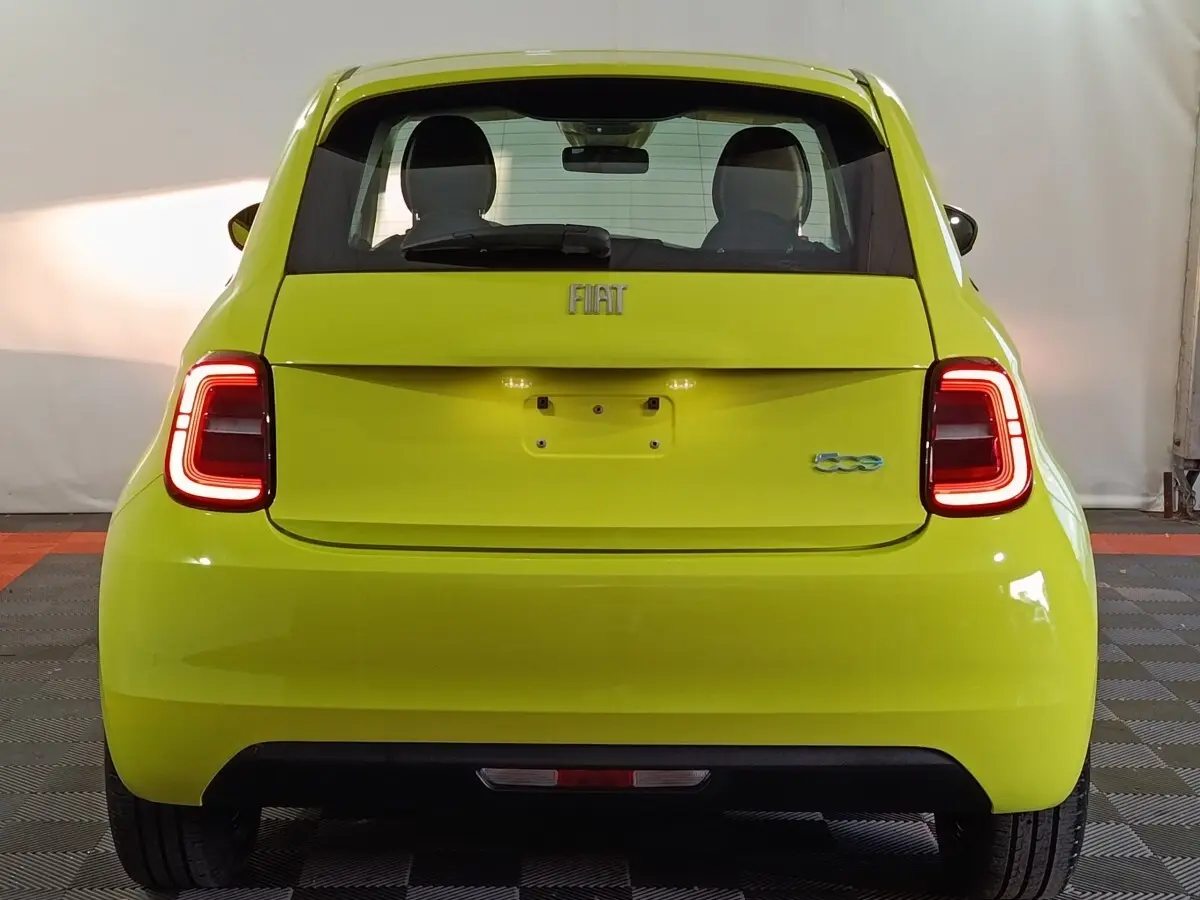 Vue arrière d'une FIAT 500 BEV 24KWH jaune vif, avec feux arrière LED allumés et logo distinctif visible.