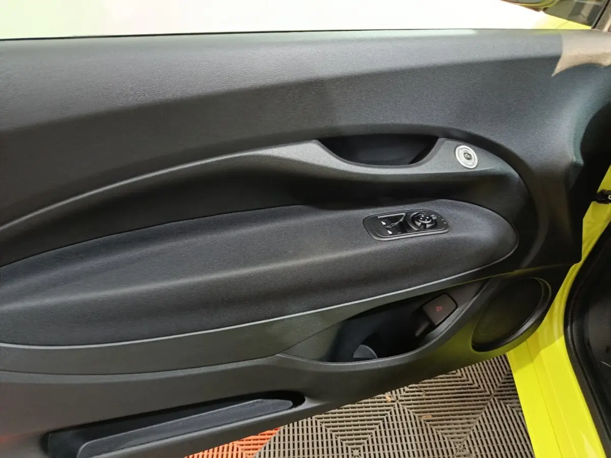 Vue intérieure côté gauche de la porte d’une FIAT 500 BEV 24KWH jaune avec commandes de vitres et haut-parleur intégré.