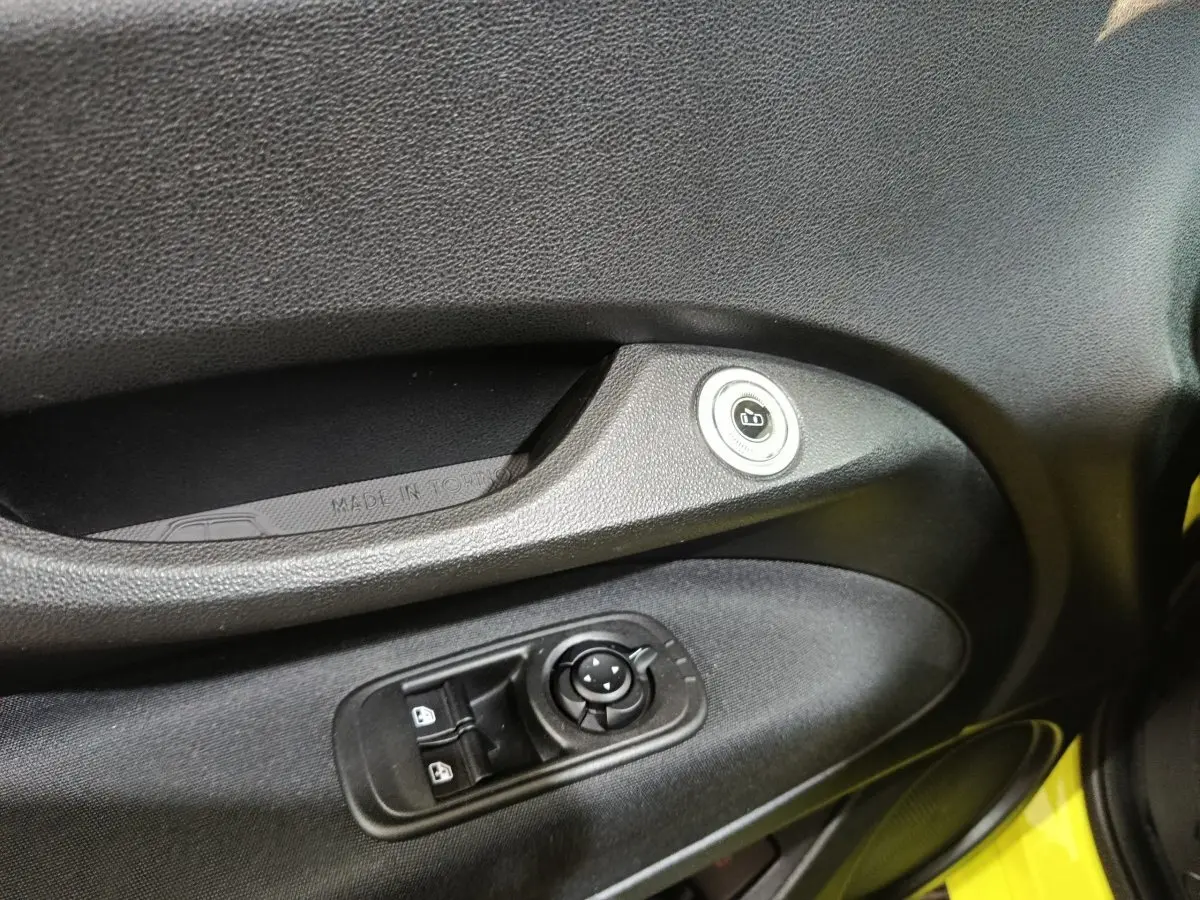 Détail de la porte côté conducteur du FIAT 500 BEV jaune 2024 avec commandes de vitres et bouton de verrouillage.
