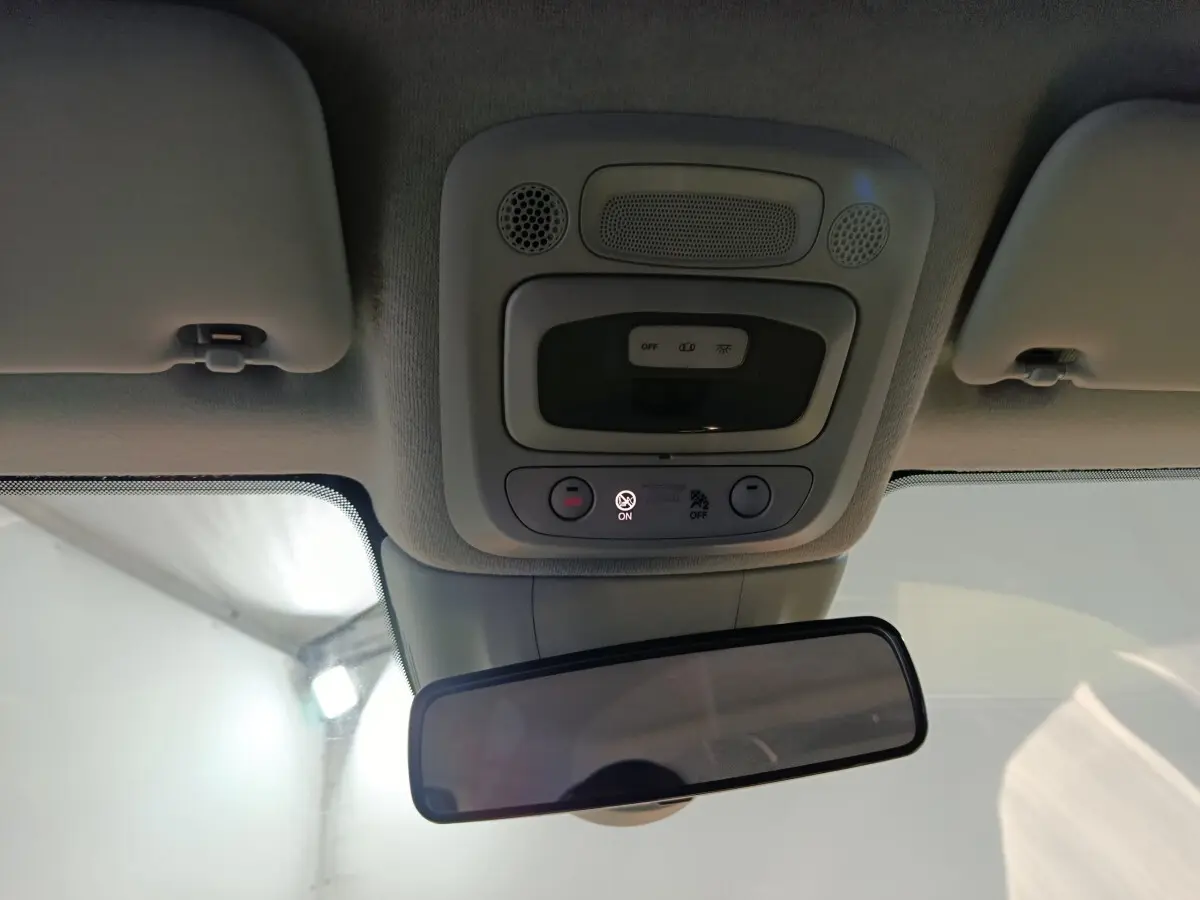 Plafonnier et rétroviseur intérieur d'une Fiat 500 BEV jaune, vue centrée vers l'avant avec commandes éclairage et alertes.