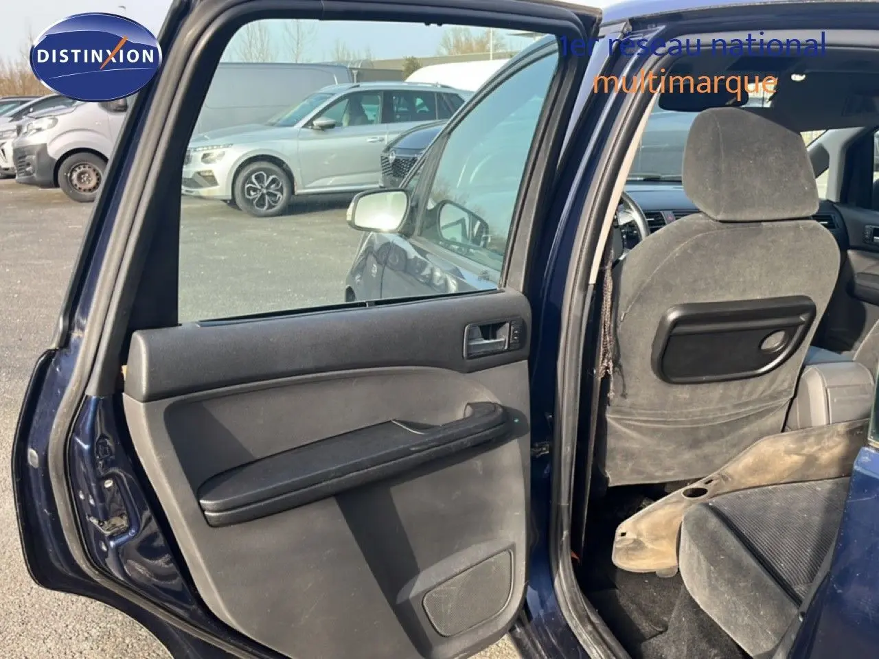 Vue intérieure côté gauche arrière d'une Ford C-MAX bleu foncé métal de 2005 avec porte ouverte et sièges en tissu gris.