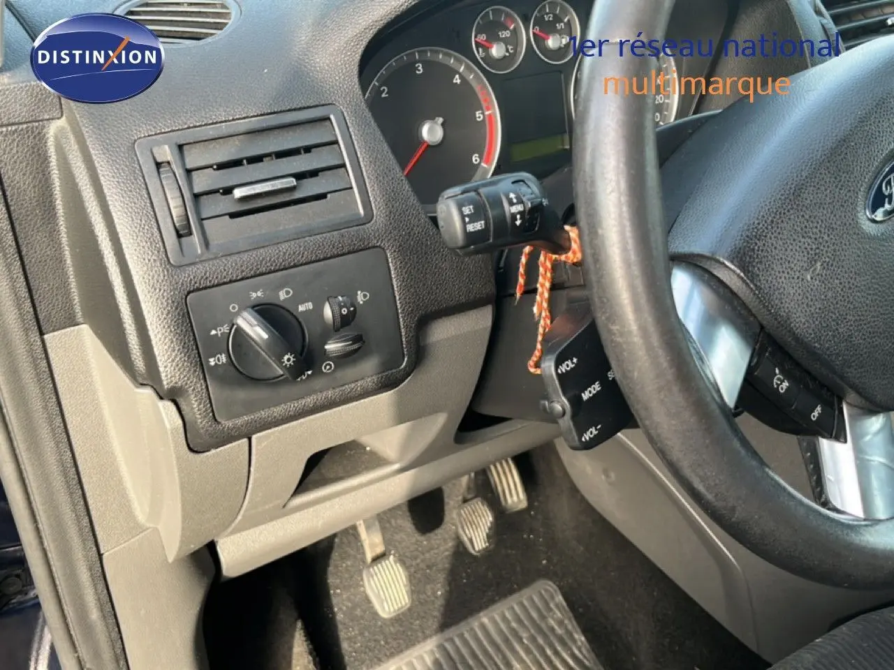 Vue intérieure côté conducteur du tableau de bord et pédales d'une Ford C-MAX 1.6 TDCI 110CH Ghia de 2005, volant noir.