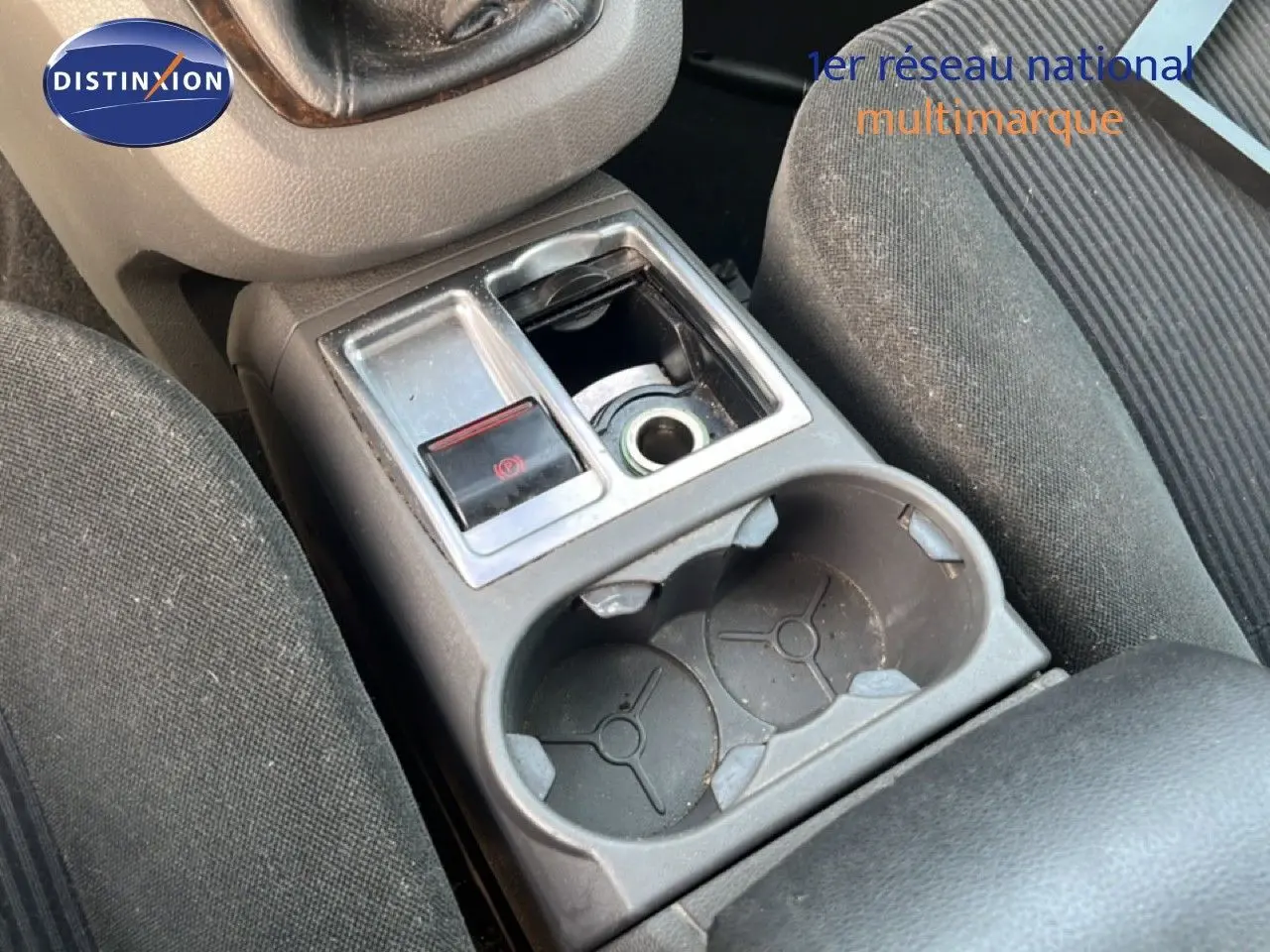 Gros plan sur la console centrale intérieure d'une Ford C-MAX 2005, montrant porte-gobelets et frein à main électrique.