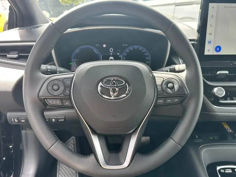 Vue rapprochée du volant multifonction noir de la Toyota Corolla 2025 avec tableau de bord digital et écran tactile.