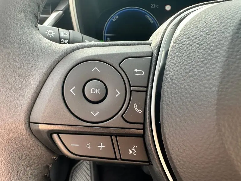 Gros plan sur les commandes multifonctions noires du volant côté gauche de la Toyota Corolla 2025 hybride.