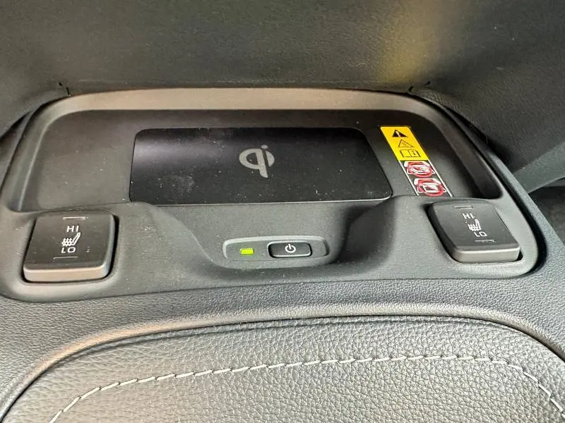 Détail du chargeur sans fil Qi et des commandes de sièges chauffants sur la console centrale d'une Toyota Corolla noire 2025.