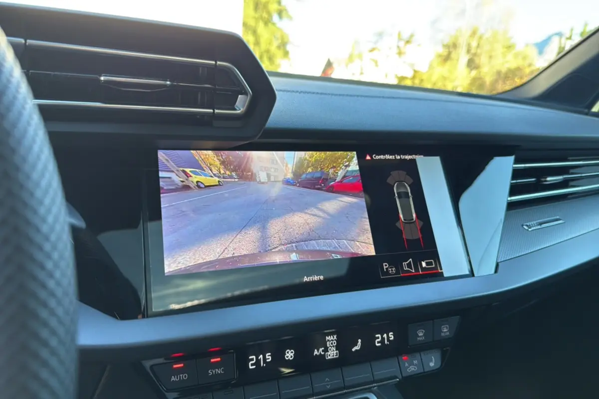Vue intérieure du tableau de bord de l'Audi A3 TFSI 150 Hybrid S-Line 2025 avec écran caméra de recul et climatisation digitale.