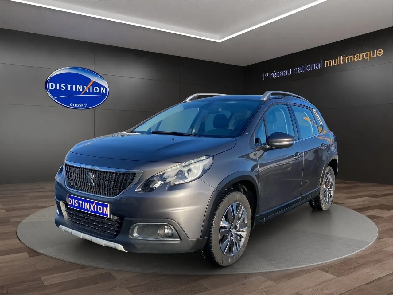 Peugeot 2008 gris platinium en 3/4 avant droit, avec calandre noire et jantes alliage visibles en showroom.