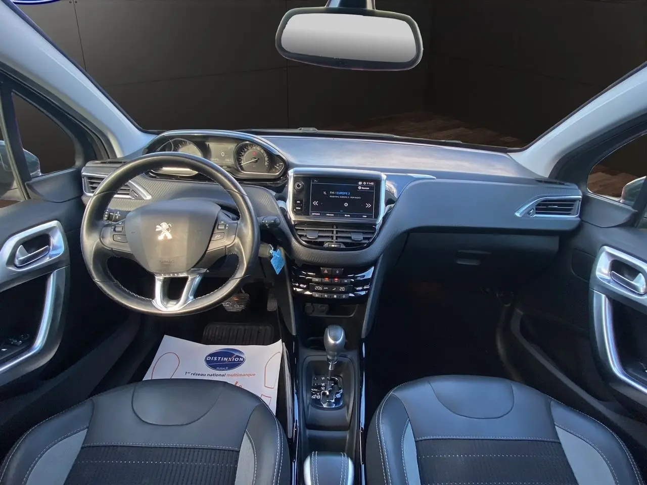 Vue intérieure avant du Peugeot 2008 gris platinium, montrant le tableau de bord, volant multifonction et console centrale avec écran tactile.