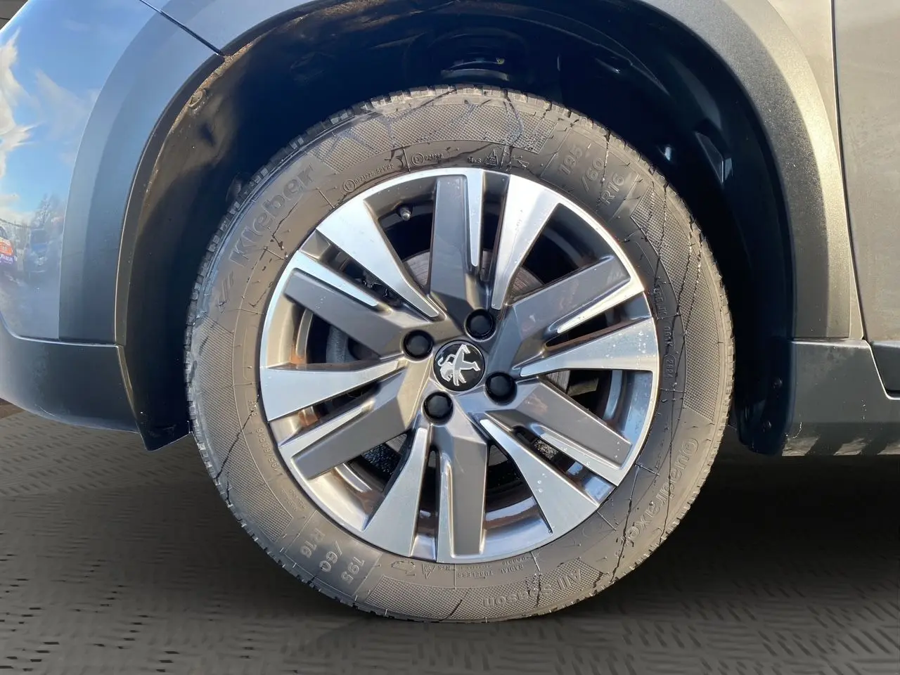 Gros plan sur la roue avant droite d’un Peugeot 2008 gris platinium avec jante alliage distinctive.